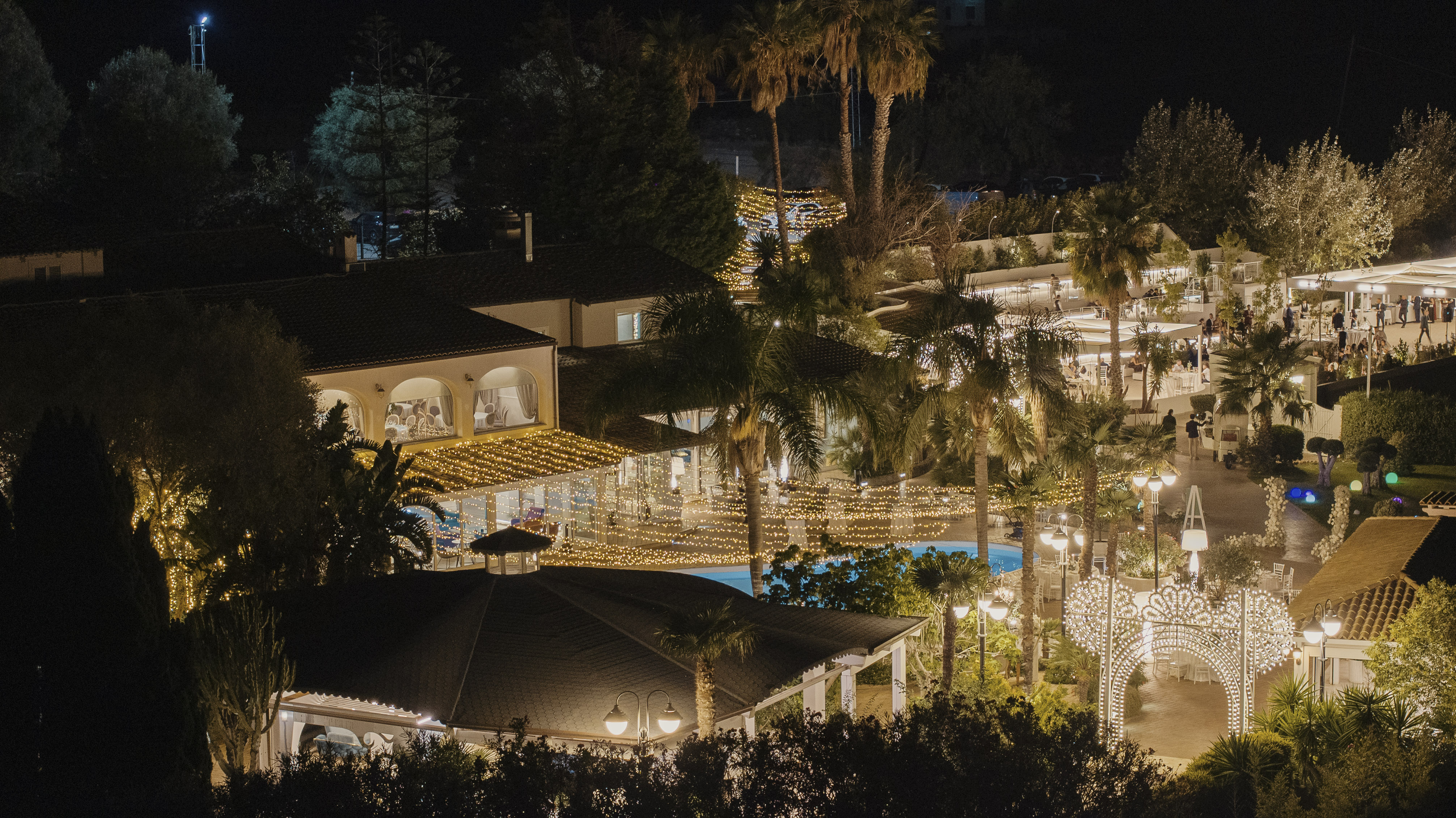 La piscina di Villa Perara tra le palme, illuminata di sera