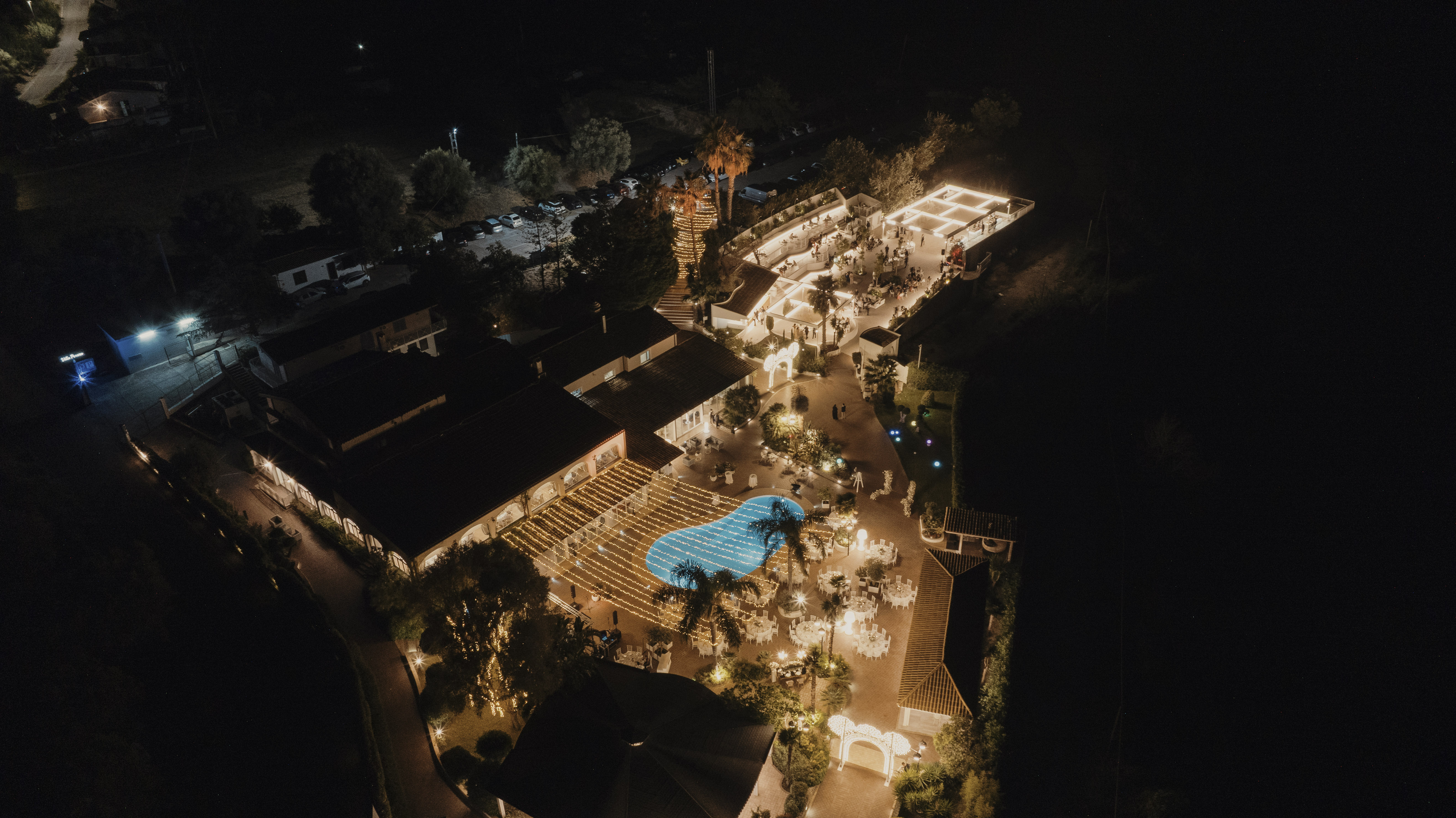 La piscina di Villa Perara illuminata di sera, tra le palme